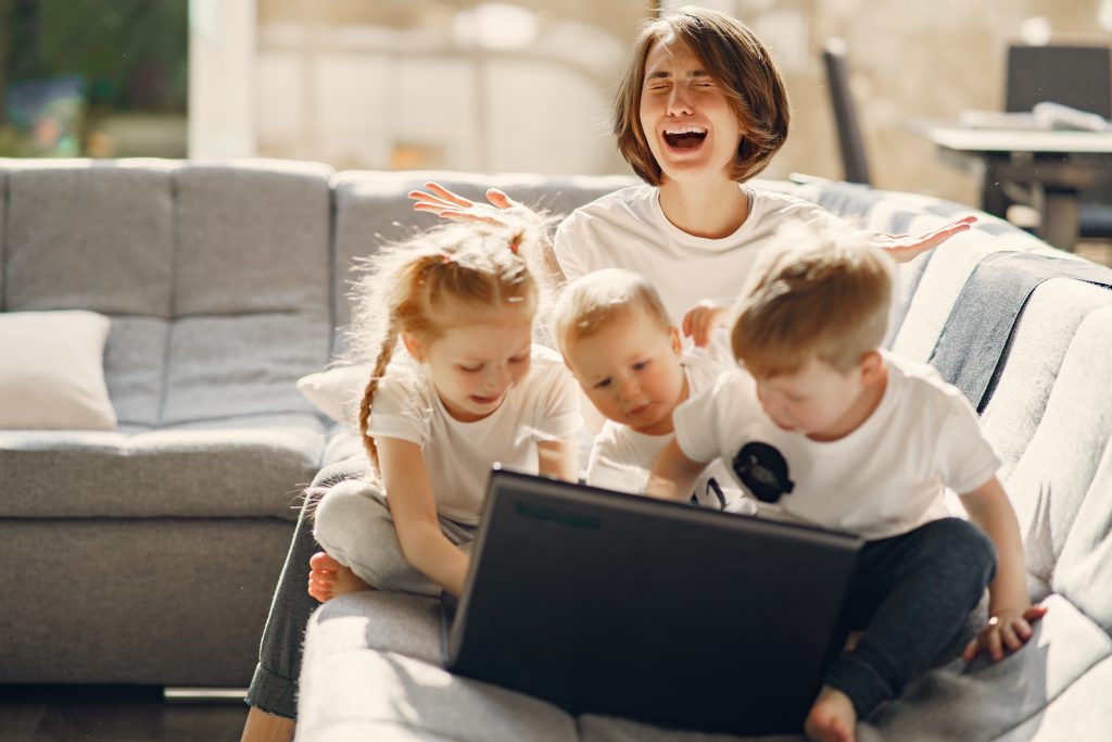 Frau am Laptop mit drei Kinder außenrum